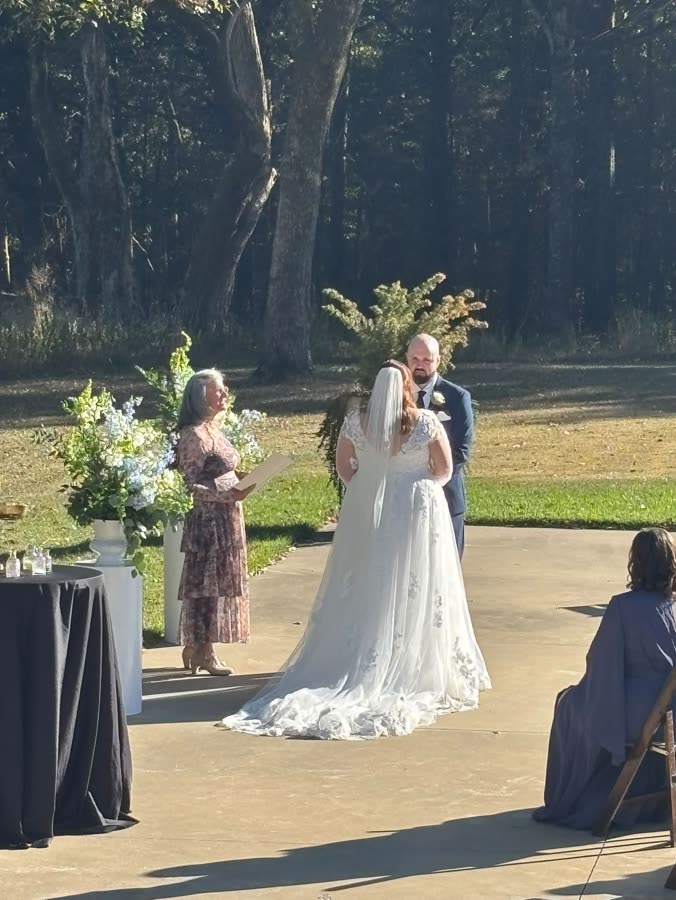 Beth officiating an outdoor wedding ceremony under the trees